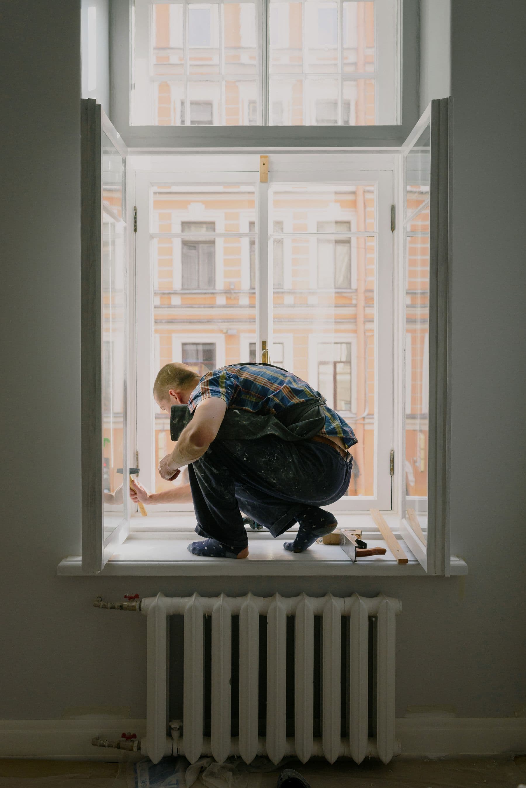 Handyman carefully repairing a window inside a home